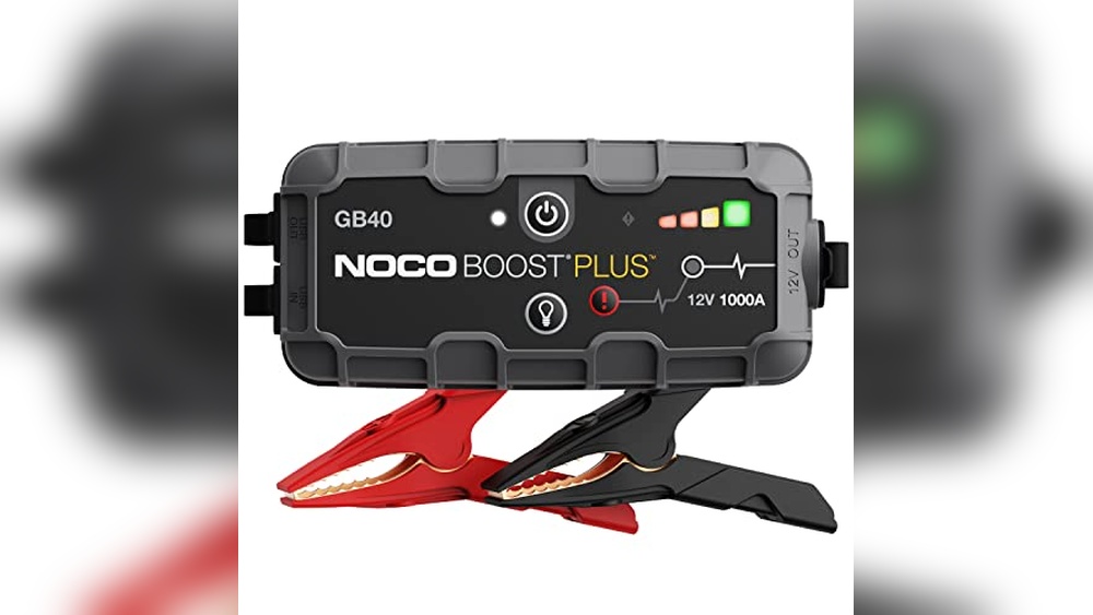 A NOCO Boost Plus GB40 portable jump starter with attached red and black battery clamps, featuring indicator lights and control buttons on its front panel.