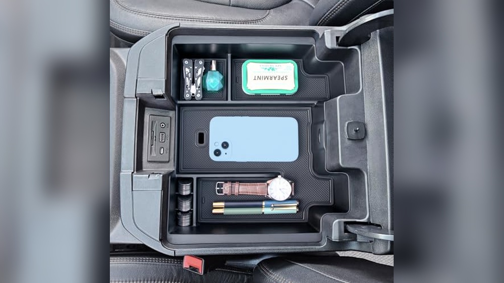 A multi-level center console organizer installed in a GMC Sierra 1500, showing separate compartments for a phone, coins, and tools.