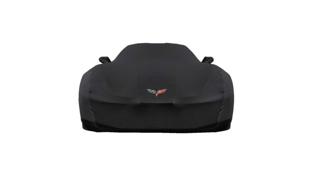 A tailored car cover protects a C6 Corvette parked inside a modern garage.