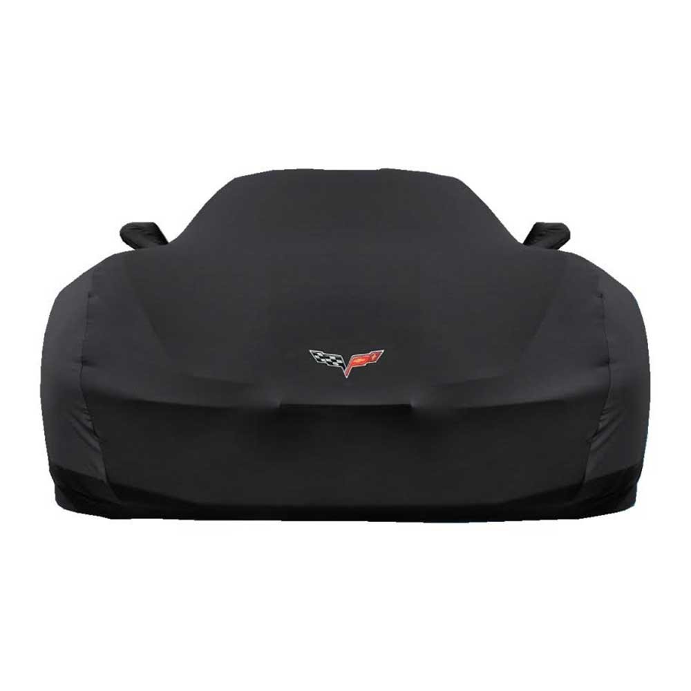 A tailored car cover protects a C6 Corvette parked inside a modern garage.