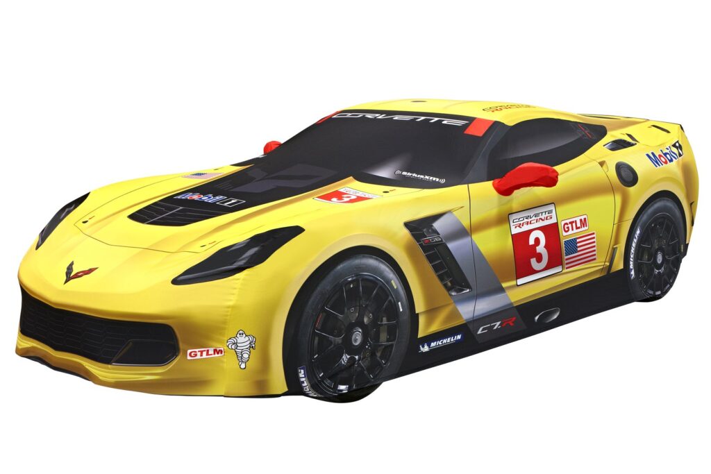 A custom car cover protects a C7 Corvette parked inside a modern garage.
