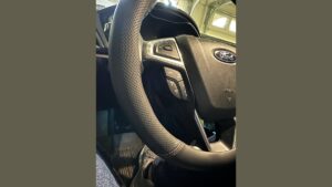 A premium leather steering wheel cover being installed on a Ford Fusion steering wheel.