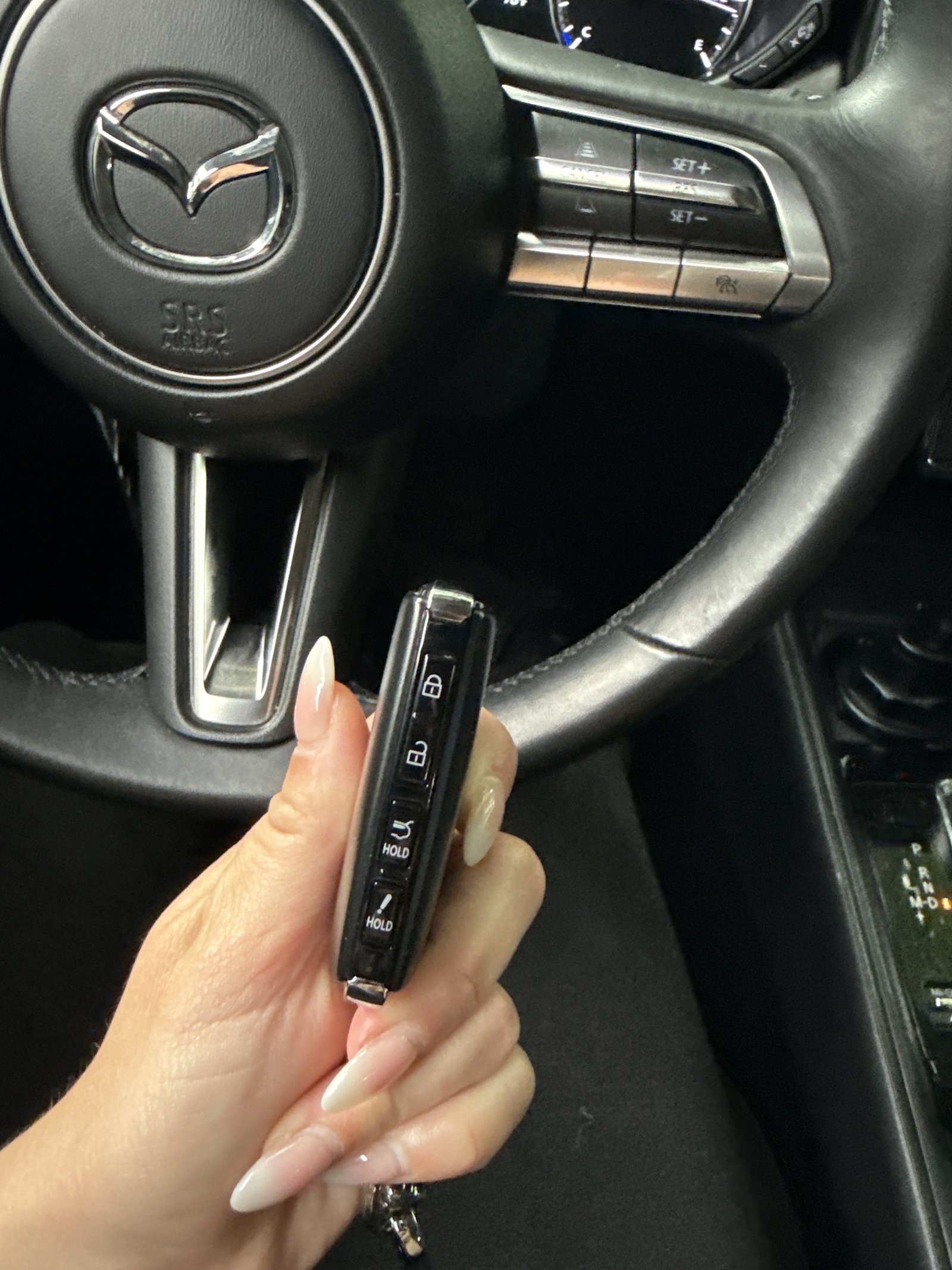 A Mazda key fob and owner manual sit on a desk for reference.