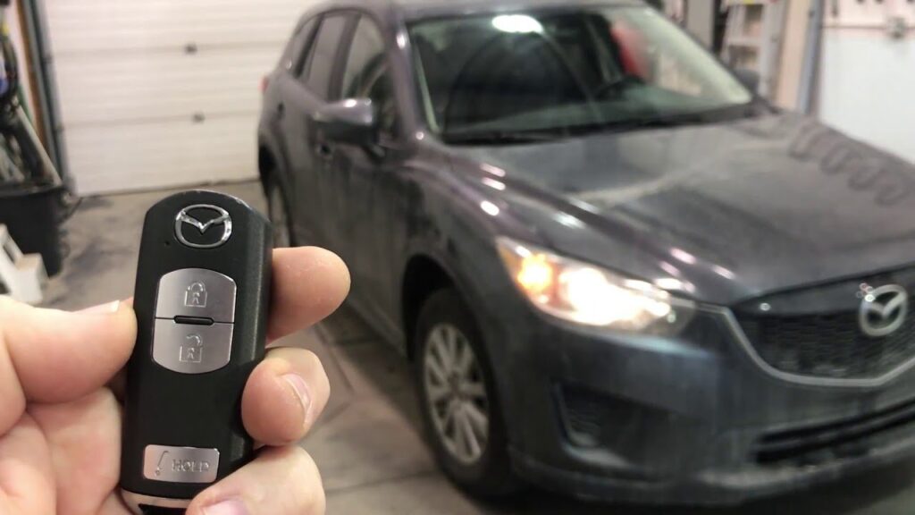 A person prepares to remote start a Mazda CX-5 using a key fob.
