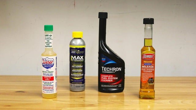A mechanic pours fuel injector cleaner into a modern Ford Fusion sedan.