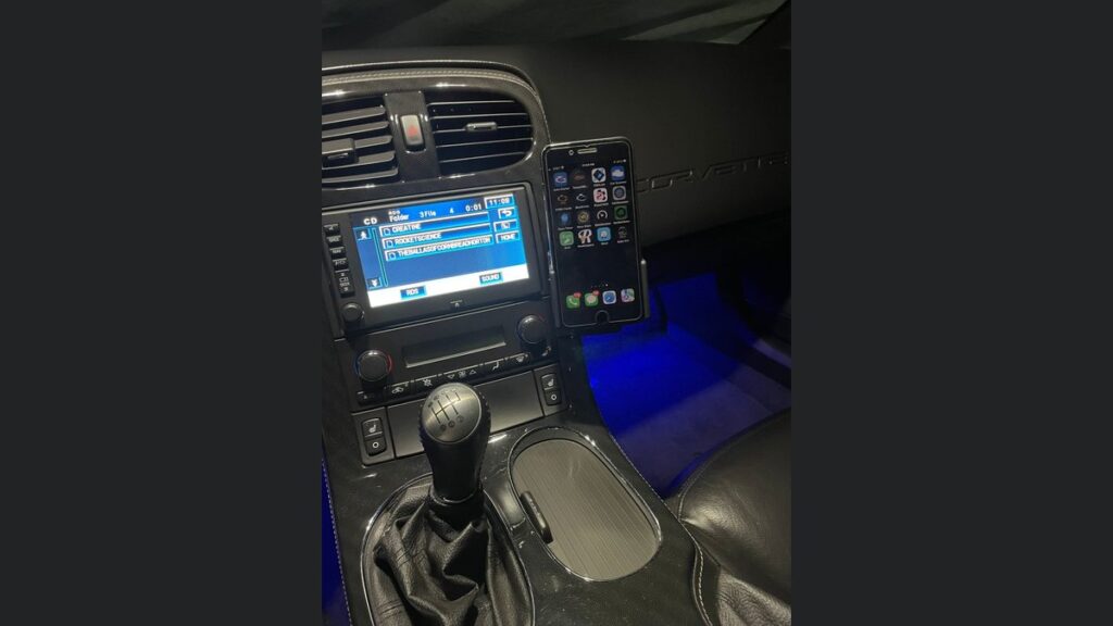 A smartphone mount securely attached inside the driver-focused cockpit of a C6 Corvette.