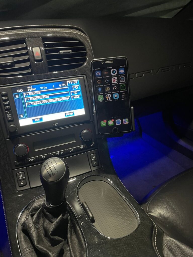 A smartphone mount securely attached inside the driver-focused cockpit of a C6 Corvette.