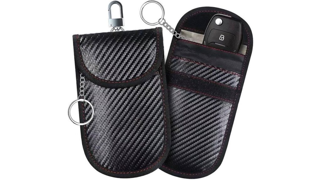 A black Faraday bag key fob protector sitting beside a Toyota car key.