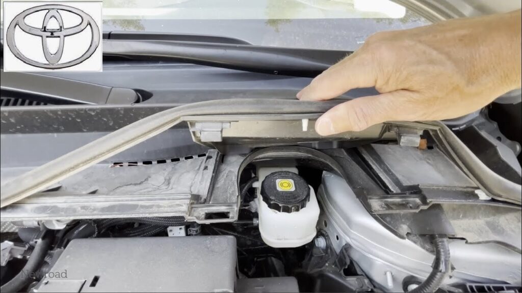 Brake fluid bottle beside an open car hood in a garage