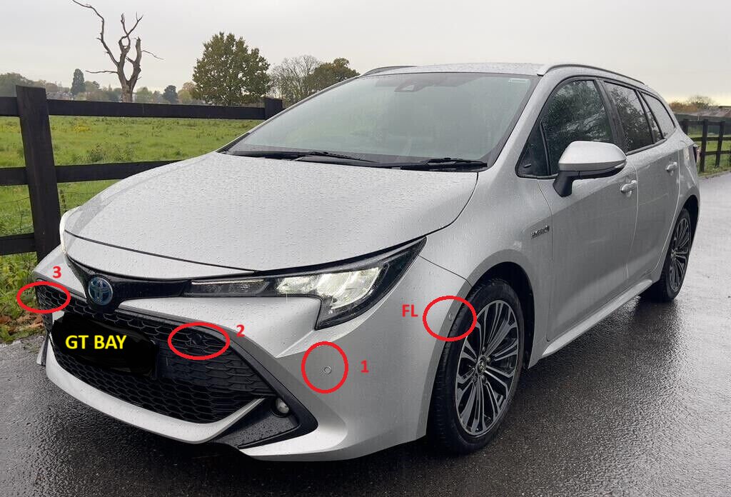 Close-up of parking sensors on the rear bumper of a silver Toyota Corolla.