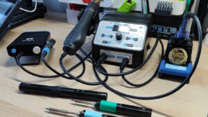 Hands soldering an automotive wire with a soldering iron on a workbench