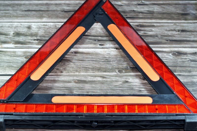 A reflective roadside warning triangle stands behind a parked Ford Fusion on a road.