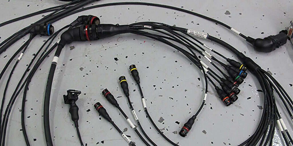 Soldering iron joining a wire on an automotive wiring harness at the workbench