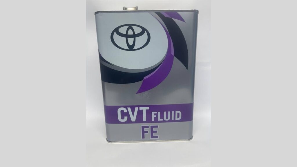 Toyota CVT fluid bottle beside drain pan and funnel in a garage